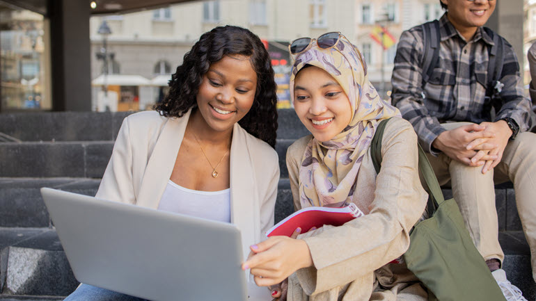 Studenten sehen sich KI-Fehlübersetzungen auf einem Laptop an und lachen darüber